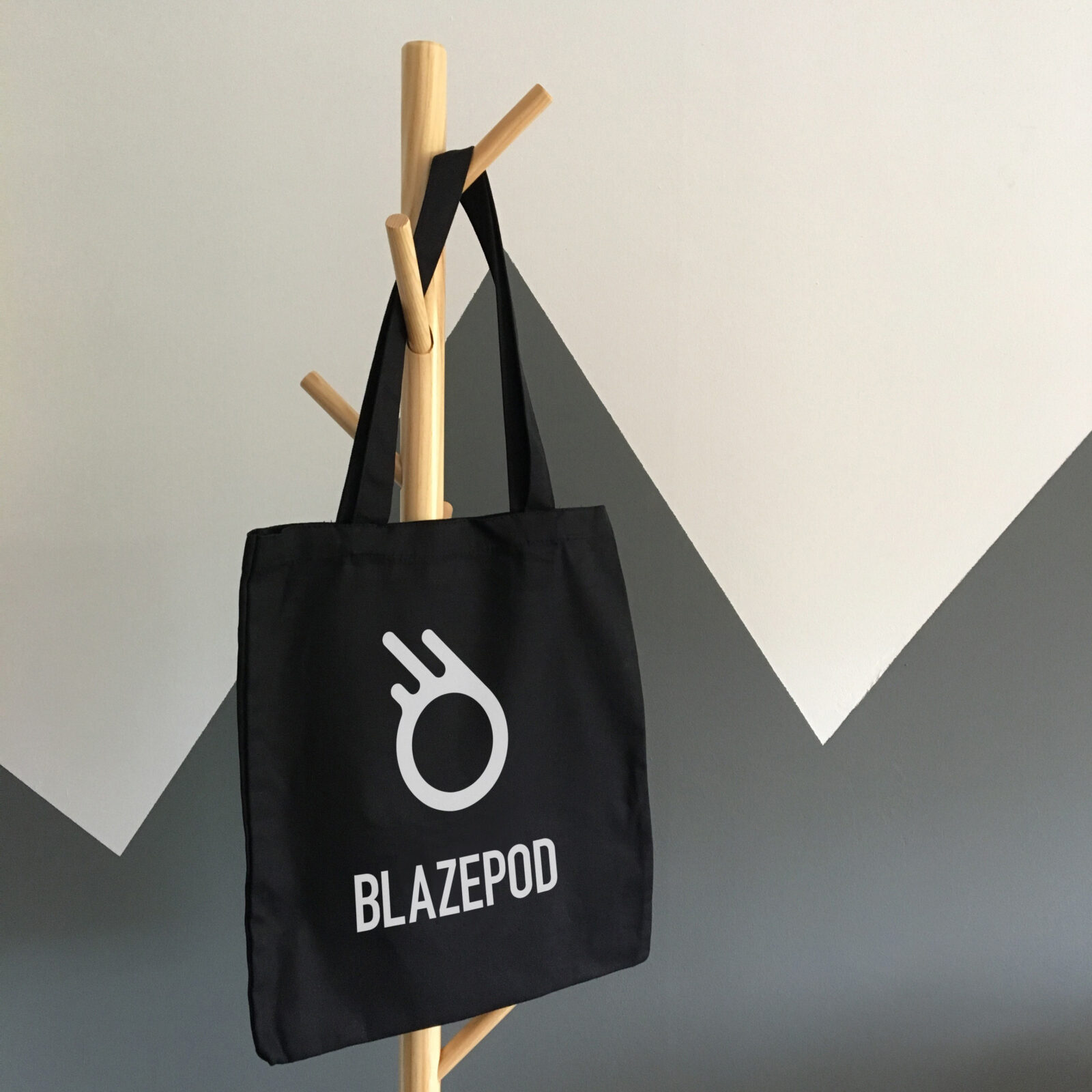 A branded black tote bag hanging on a coat rack