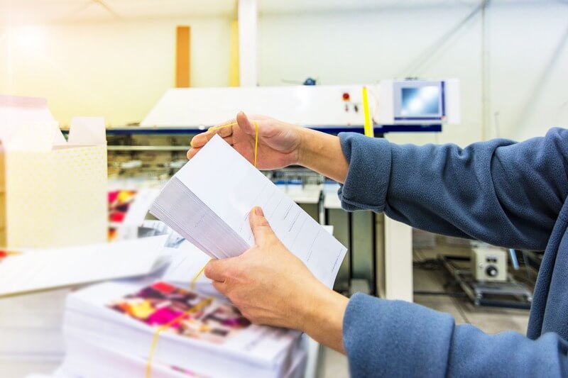 A worker bundles stacks of direct mail materials