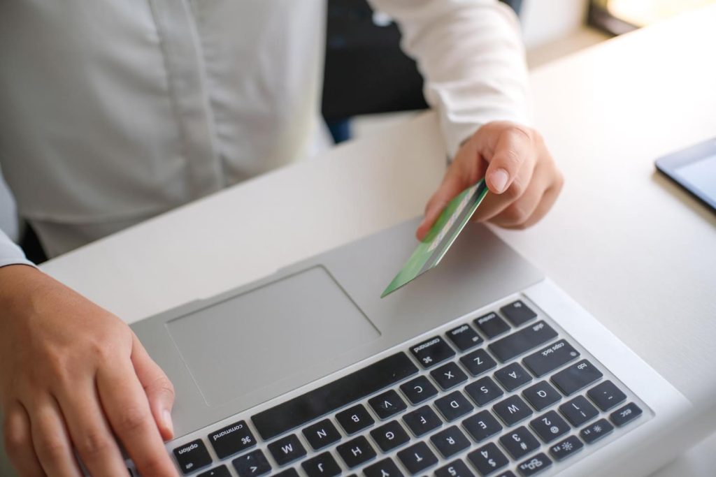 Top view of laptop and man holding a credit card. 