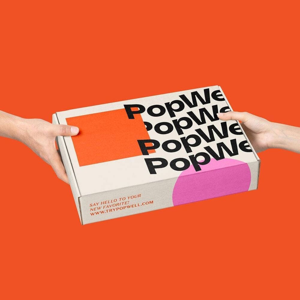 PopWell box on ornage background being held by hands. 