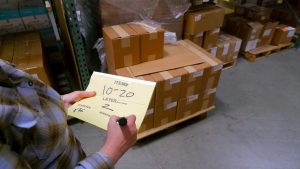 Woman writing on STiCKiPad in a warehouse by boxes.