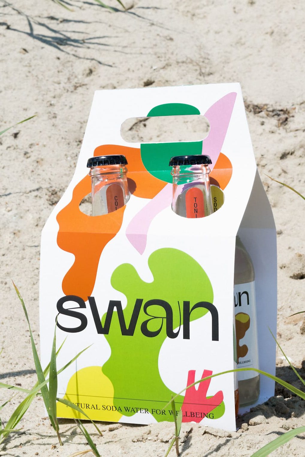 Swan bottle carrying case with Swan branding photographed in the sand.