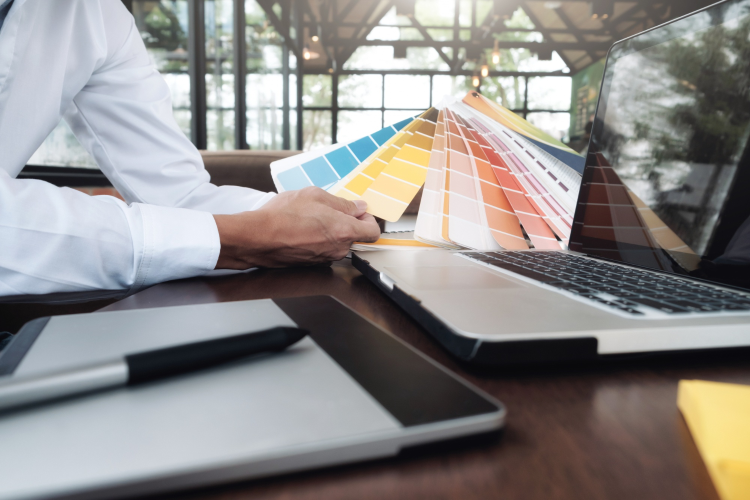 Pantone Swatches being held by a man near his computer.