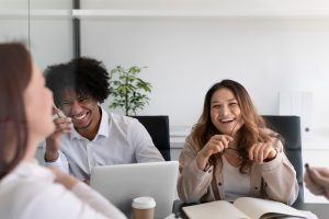 People laughing at a desk in a workplace.